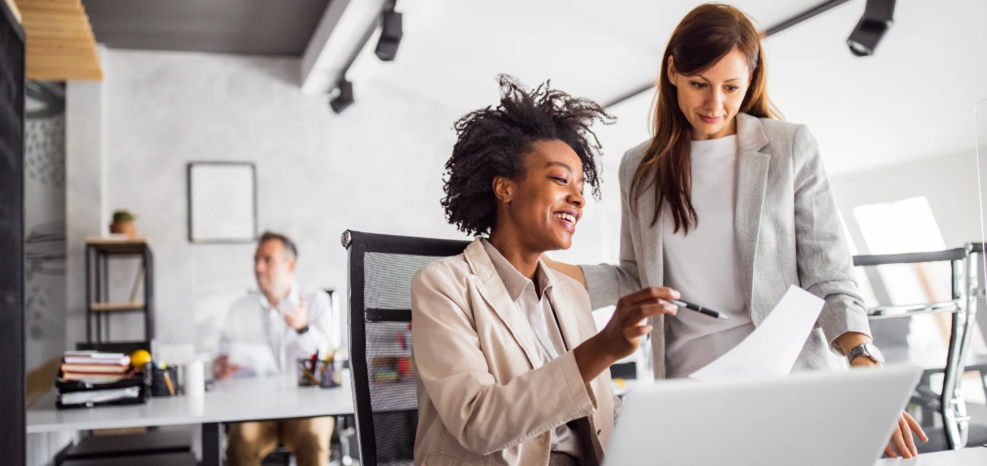 Two HR professionals reviewing a candidate's resume on a laptop