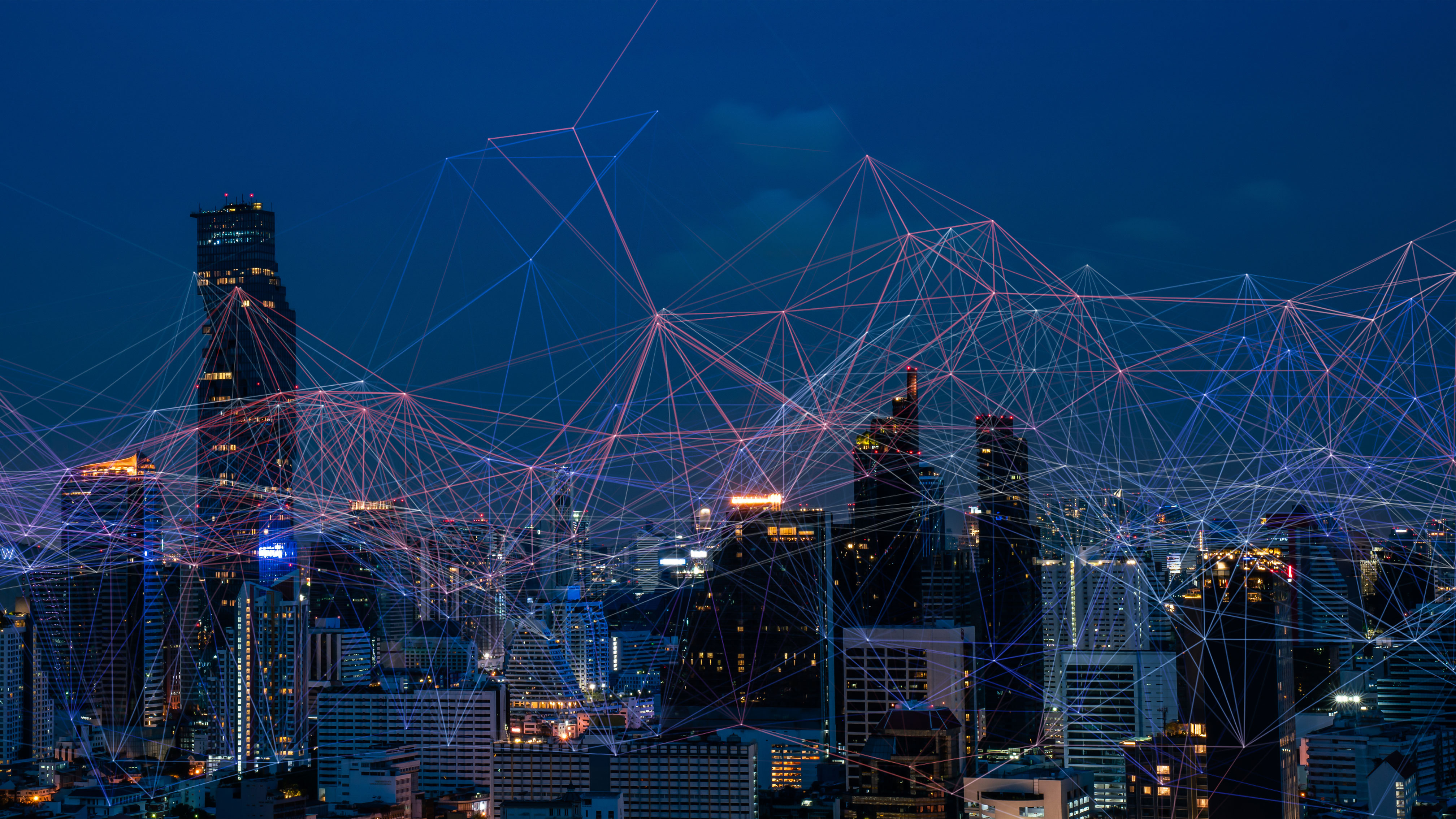 Urban skyline at night with connected digital network visualisation representing enterprise networking, digital workplace solutions and business technology innovation.